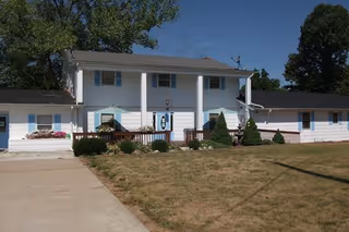 White two-story assisted living facility with central entrance and manicured lawn