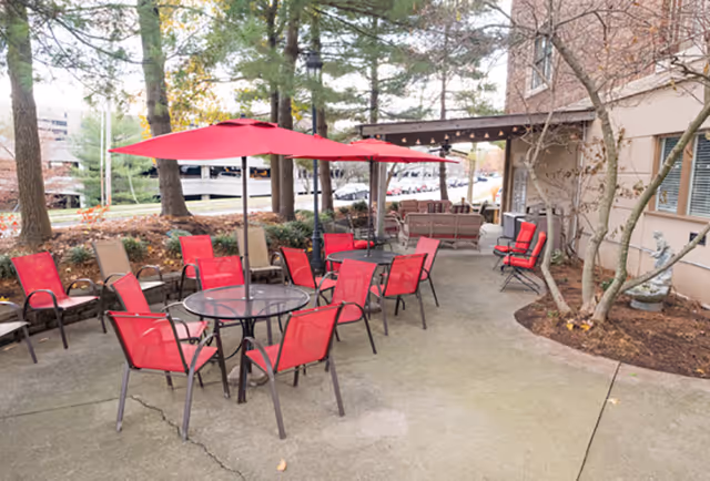 Outdoor patio at The Lafayette with red chairs and tables under red umbrellas beside the building.