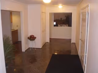 Marble-floored entrance hallway with a reception window at the far end, doors on either side, and a small table with decor.