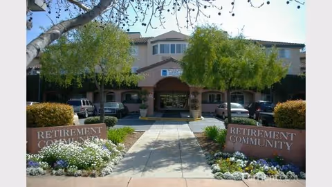 Front exterior of Carlton Senior Living Fremont with entrance path and landscaping.
