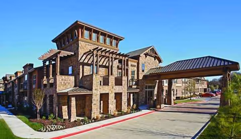 Stone senior living facility with a large covered entrance and drive lane.