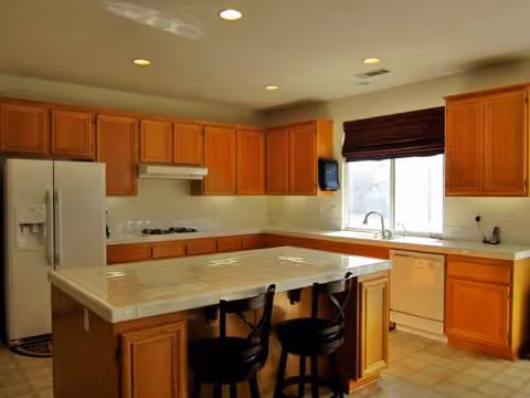 Cozy kitchen with island, wooden cabinets, and stainless steel appliances in a senior living facility.