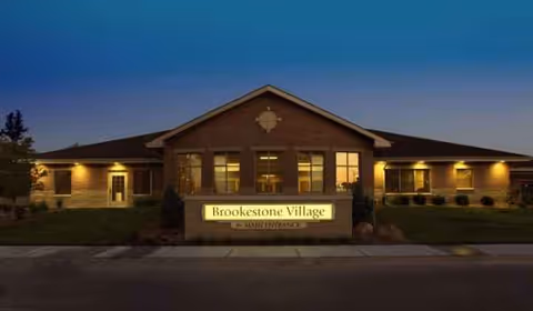 Evening exterior of Brookestone Village senior living facility with illuminated front sign