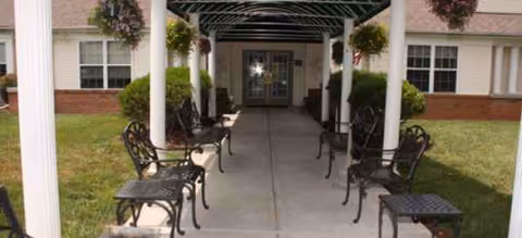 Covered walkway with benches and hanging baskets leads to the Cardinal Senior Communities at Roanoke entrance.