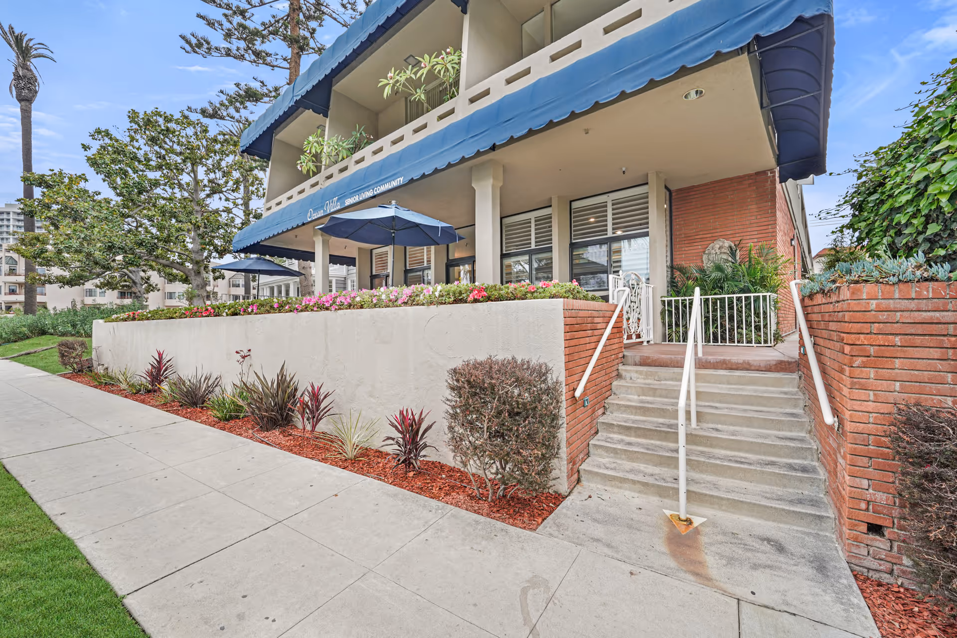 Exterior view of the Meridian at Ocean Villa & Bella Mar senior living facility with landscaping and stairs leading to the entrance.