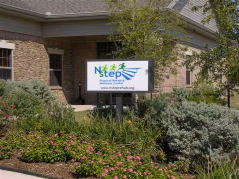 Brick facility exterior with a lawn sign advertising a rehab and wellness center.