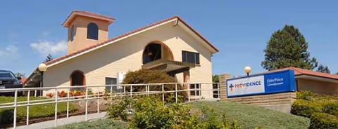 Tan building with a sloped roof, ramp, and Providence ElderPlace sign at the front.