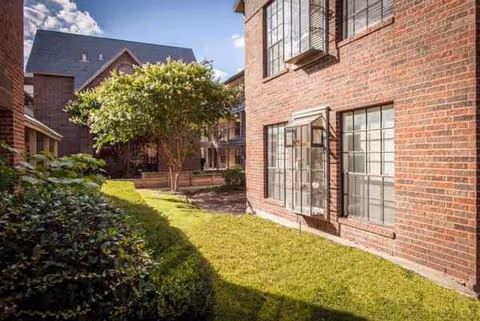 Brick senior living building with green lawn, trees, and large windows along the exterior.