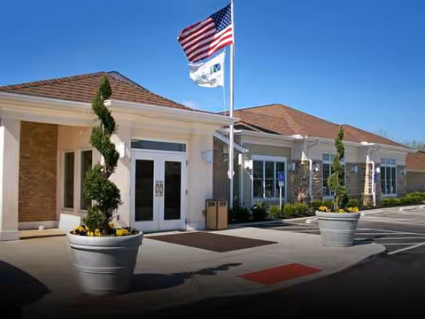 Exterior view of The Laurels of Hilliard facility entrance with flagpoles and planters.
