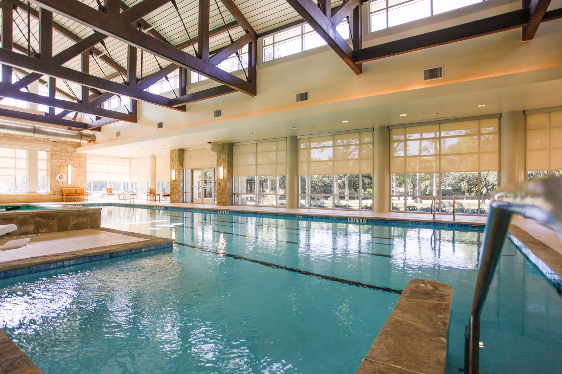 Indoor swimming pool in a community facility with high beamed ceiling and large windows.