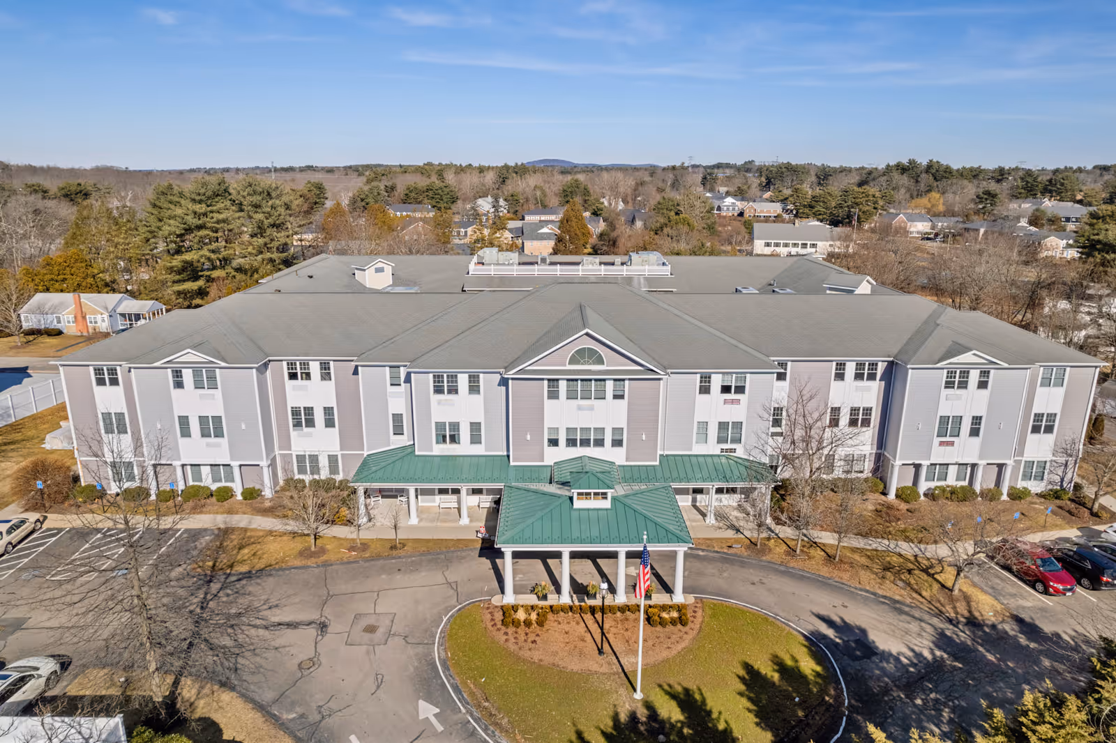 Aerial view of the three-story Brookmeadow at Cobb Corner building showing a covered entrance, circular driveway, and surrounding landscaping.