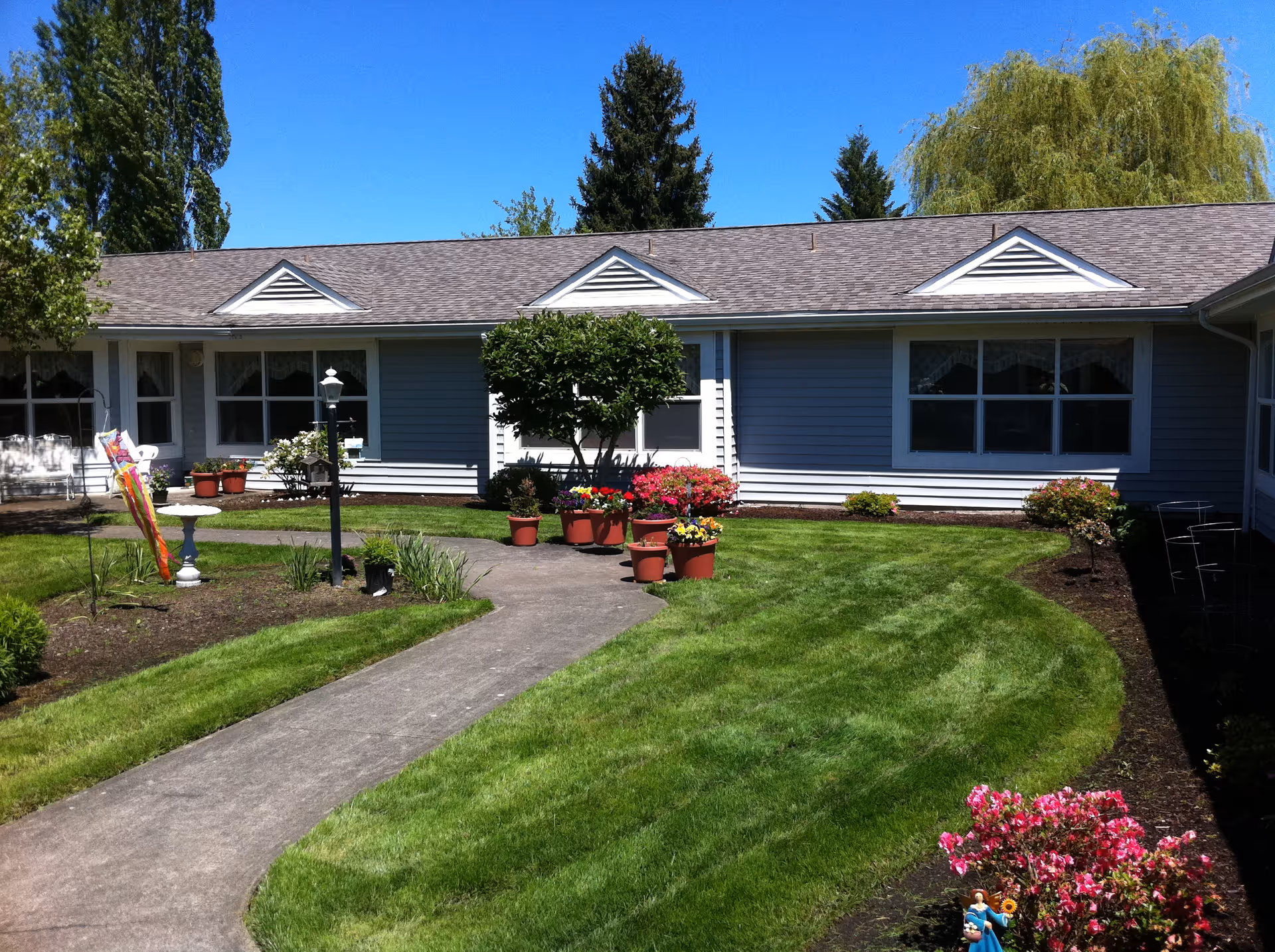 A well-maintained garden area with pathways and flower pots outside a senior living facility.