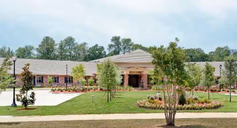Front view of a single-story senior living facility with landscaped entrance and green lawn.