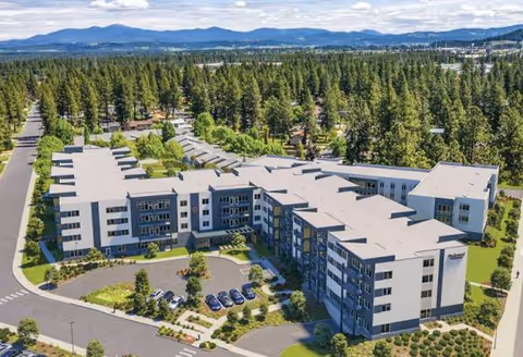 Aerial view of a large, modern senior living campus with parking and trees.