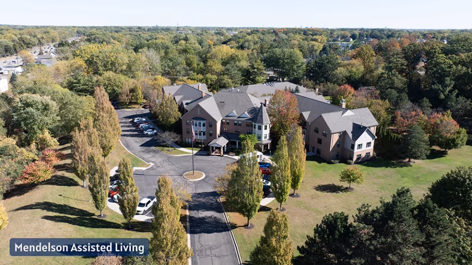 Aerial view of a multi-wing senior living campus with a circular driveway and surrounding trees.
