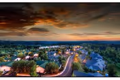 Aerial view of a retirement community at sunset with homes lining a winding road surrounded by trees.