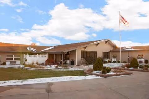 Front exterior of Life Care Center of Burlington with flag, entrance, and landscaped surroundings.