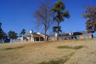 Exterior view of NorthCliff Assisted Living building on a grassy hill under blue sky.