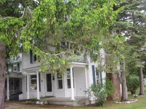 Exterior view of Majestic Manor’s white porch-front building surrounded by trees.
