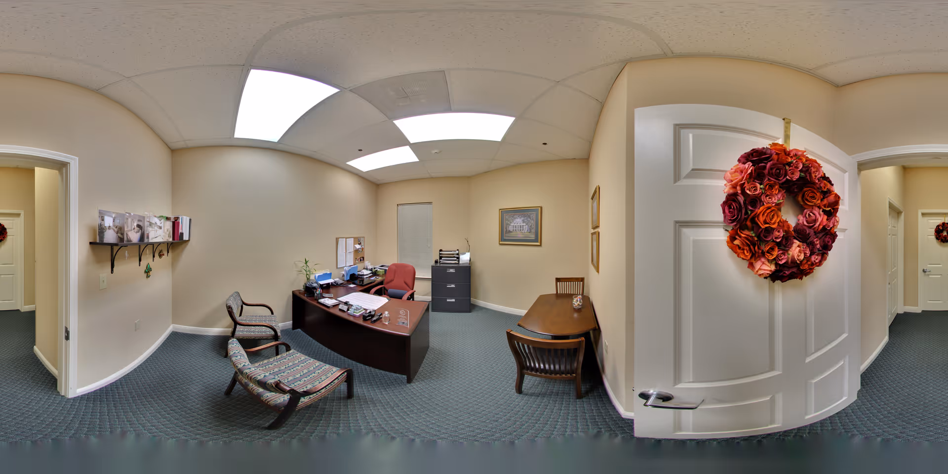 Small administrative office in a senior living community with desks, chairs, filing cabinet, and a door decorated with a floral wreath.