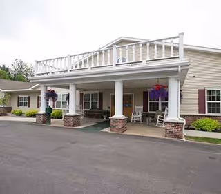 Front entrance of senior living facility with a covered porch and hanging baskets.