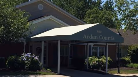 Exterior view of Arden Courts Wayne entrance with a covered walkway and surrounding shrubbery.