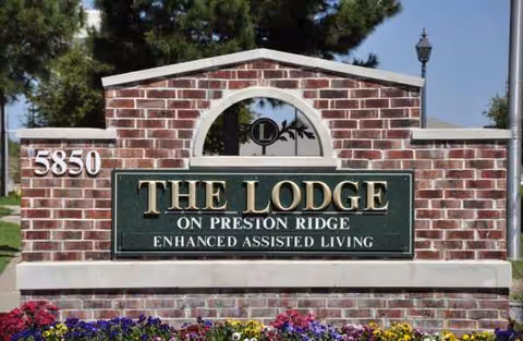 Brick entrance sign for The Lodge on Preston Ridge, with colorful flowers.