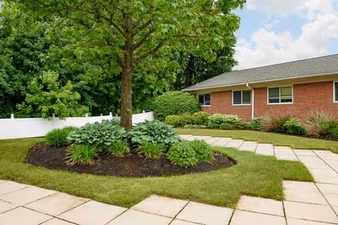 Front exterior of a brick senior living facility with a circular garden and walkway.