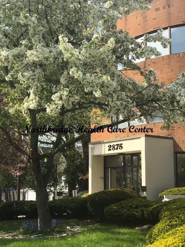 Exterior view of Northbridge Health Care Center with flowering trees and landscaping.