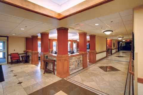 Interior lobby with red columns, seating, and a hallway in a senior living facility.