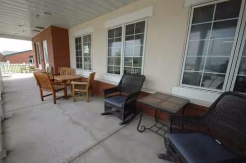 Outdoor patio seating area with wooden chairs and wicker furniture against a building.