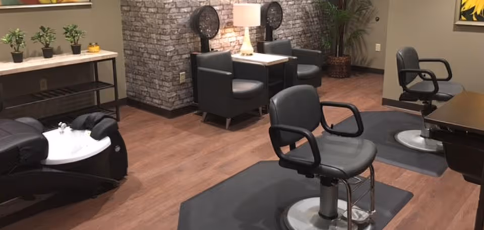 Salon-style room with styling chairs, a shampoo sink, and seating in a cozy interior space.
