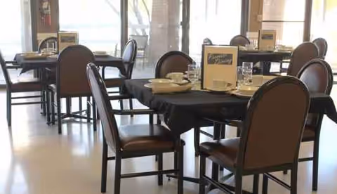 A dining room in a senior living facility with multiple tables set for meals.
