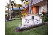 Front exterior of Crystal Cove Care Center with a landscaped sign and palm trees.