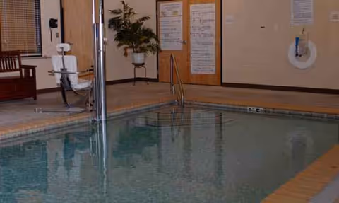 Indoor pool area in Regency at the Park with chairs, plants, and wall notices.