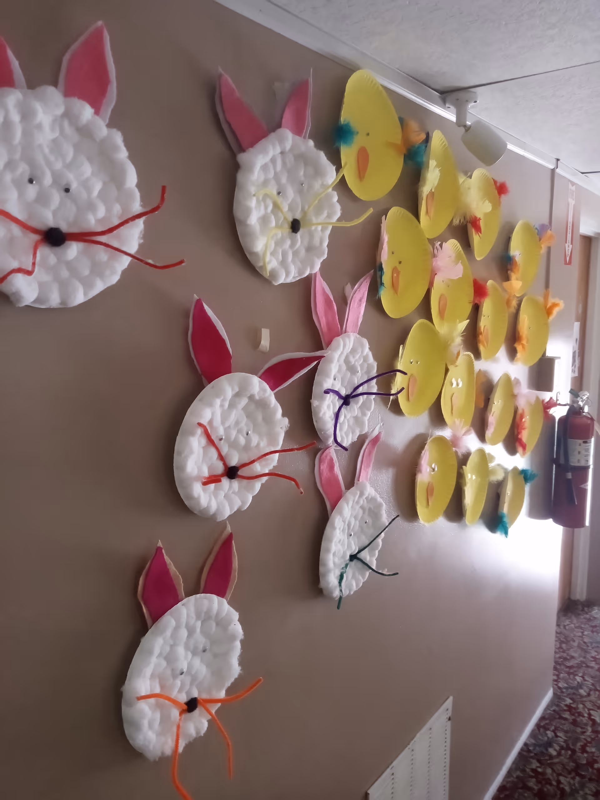 Hallway wall decorated with handmade bunny and chick paper-plate crafts.