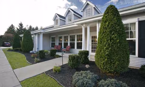 Front exterior view of Tennyson Court senior living with porch seating and landscaping.