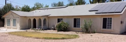 Single-story beige senior care facility with arched entry, windows, and solar panels.