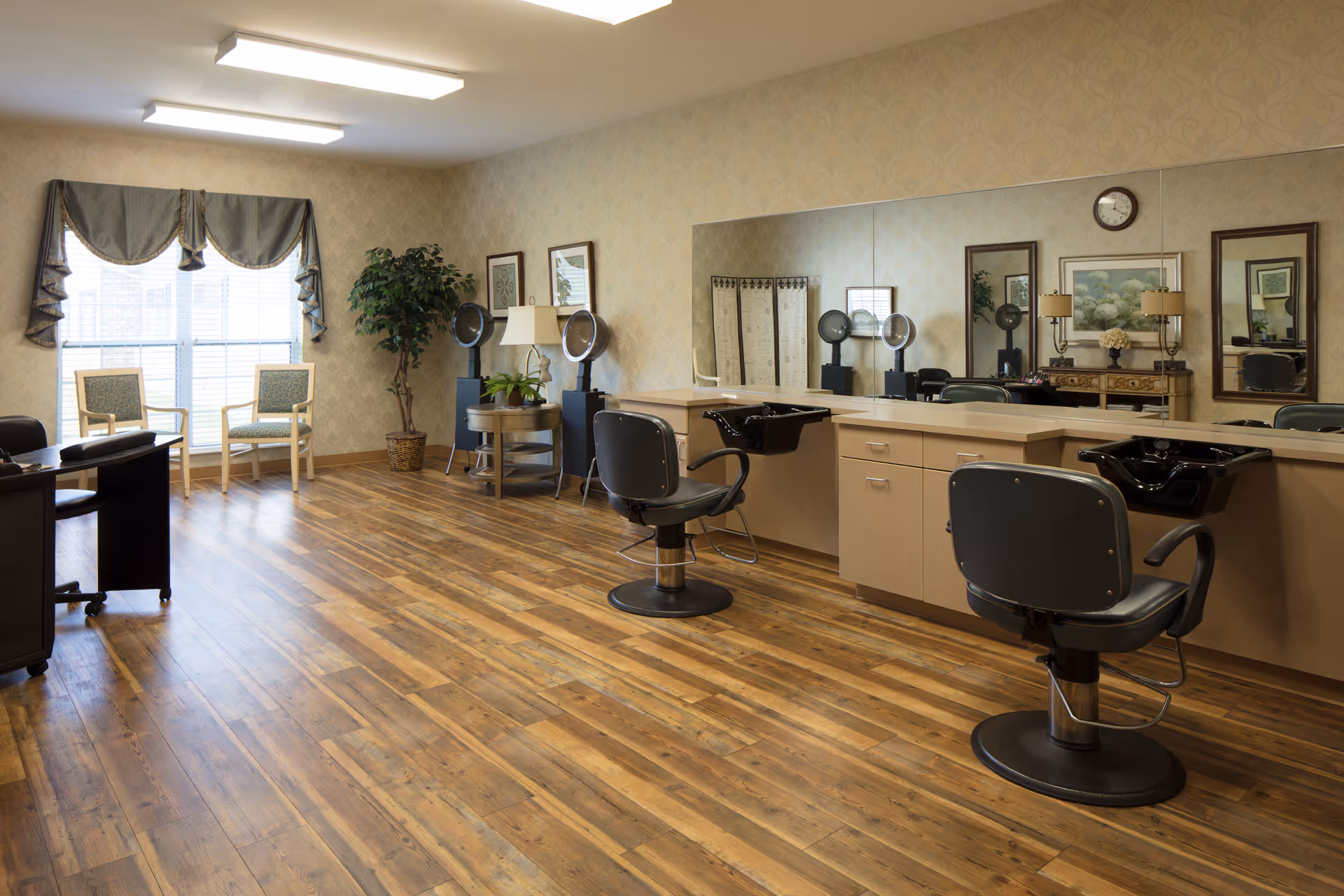 Bright salon room with styling chairs, wash basins, mirrors, and seating by a window.