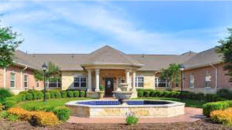 Single-story brick facility front with a central fountain, columned entrance, and landscaped grounds.