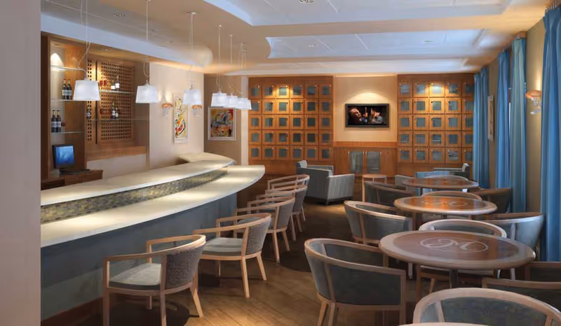 A modern communal dining/lounge room with a curved bar, pendant lighting, round tables and chairs, and a TV on the back wall.