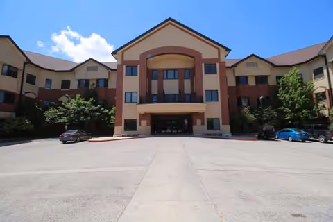 Front view of Helen Greathouse Manor senior living facility with cars in parking lot.