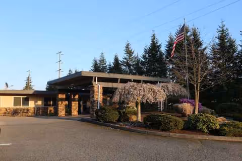 Exterior view of Emerald Hills Adult Family Home entrance with a covered porte-cochere and landscaping.