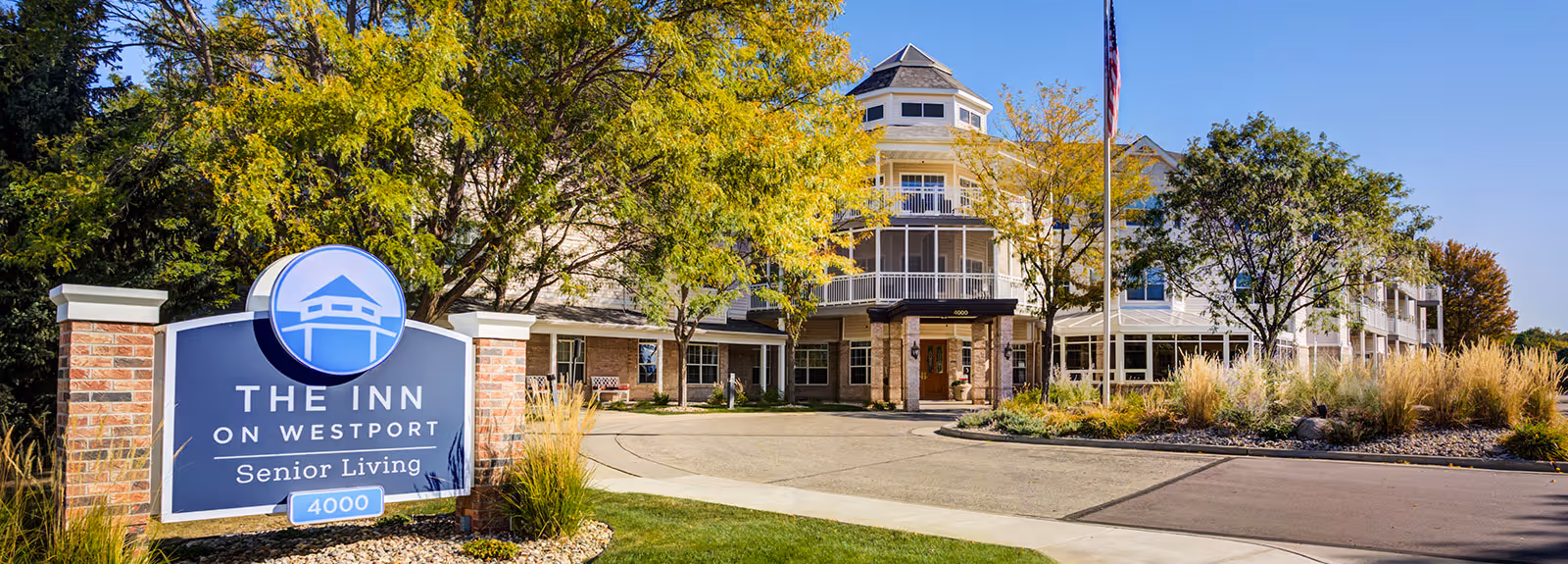 Front exterior of The Inn on Westport senior living building with entrance driveway and a large sign reading 'The Inn on Westport'.