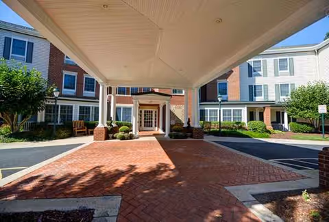 Covered entrance to Charter Senior Living of Fredericksburg with brick walkway and columns.