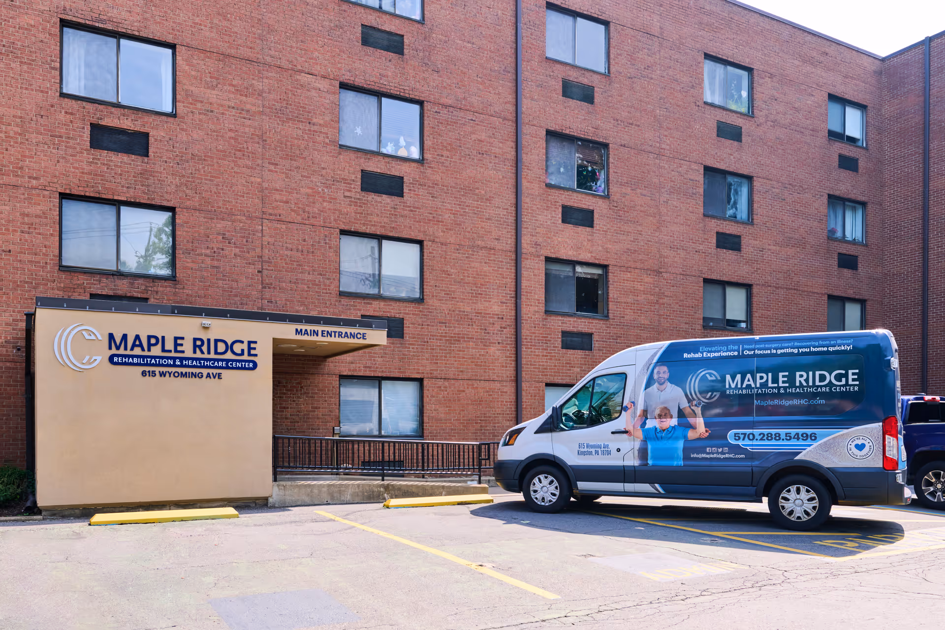 Exterior view of Maple Ridge Rehabilitation and Healthcare Center showing the main entrance sign and a branded van parked in front of the building. The building is made of red brick with several windows visible.