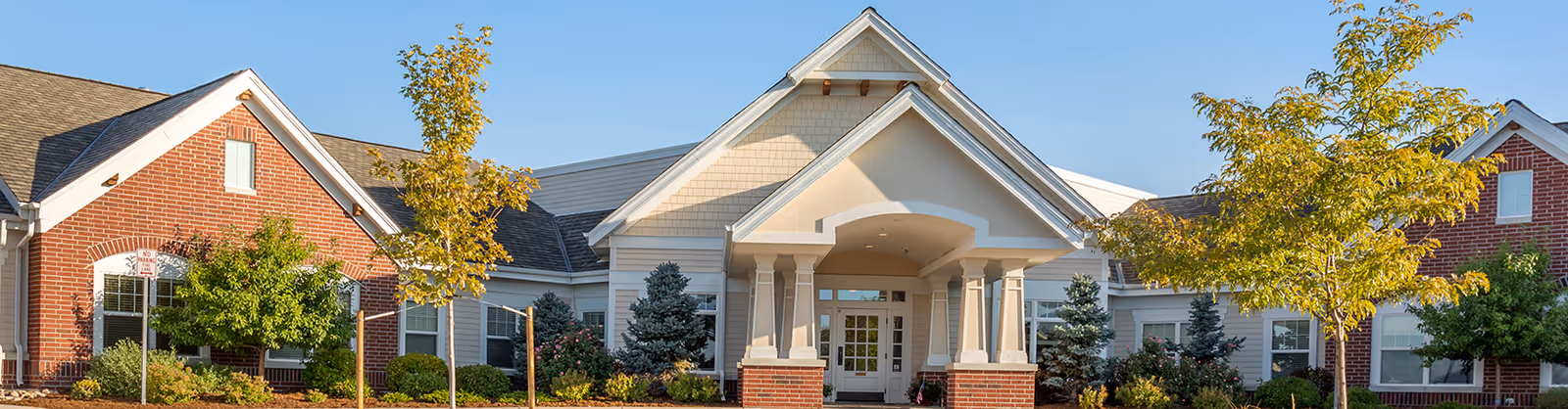 Wide exterior view of Brookdale Highlands Ranch facility with brick entrance and trees.