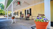 Covered outdoor porch at Cardinal Care of Hope Mills with rocking chairs and potted flowers.