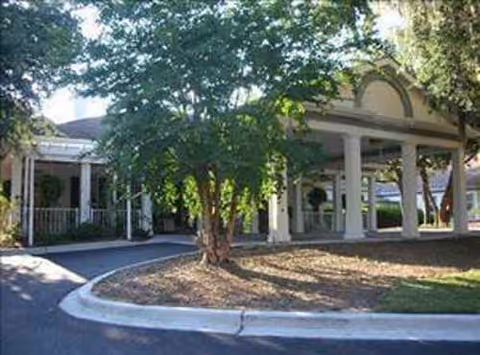Exterior view of River Oaks senior living facility with a covered entrance and greenery.