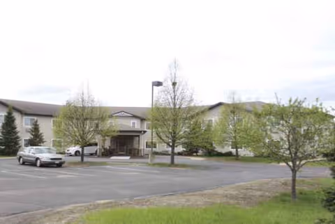 Exterior view of Oak Gardens Place with a parking lot and trees in front
